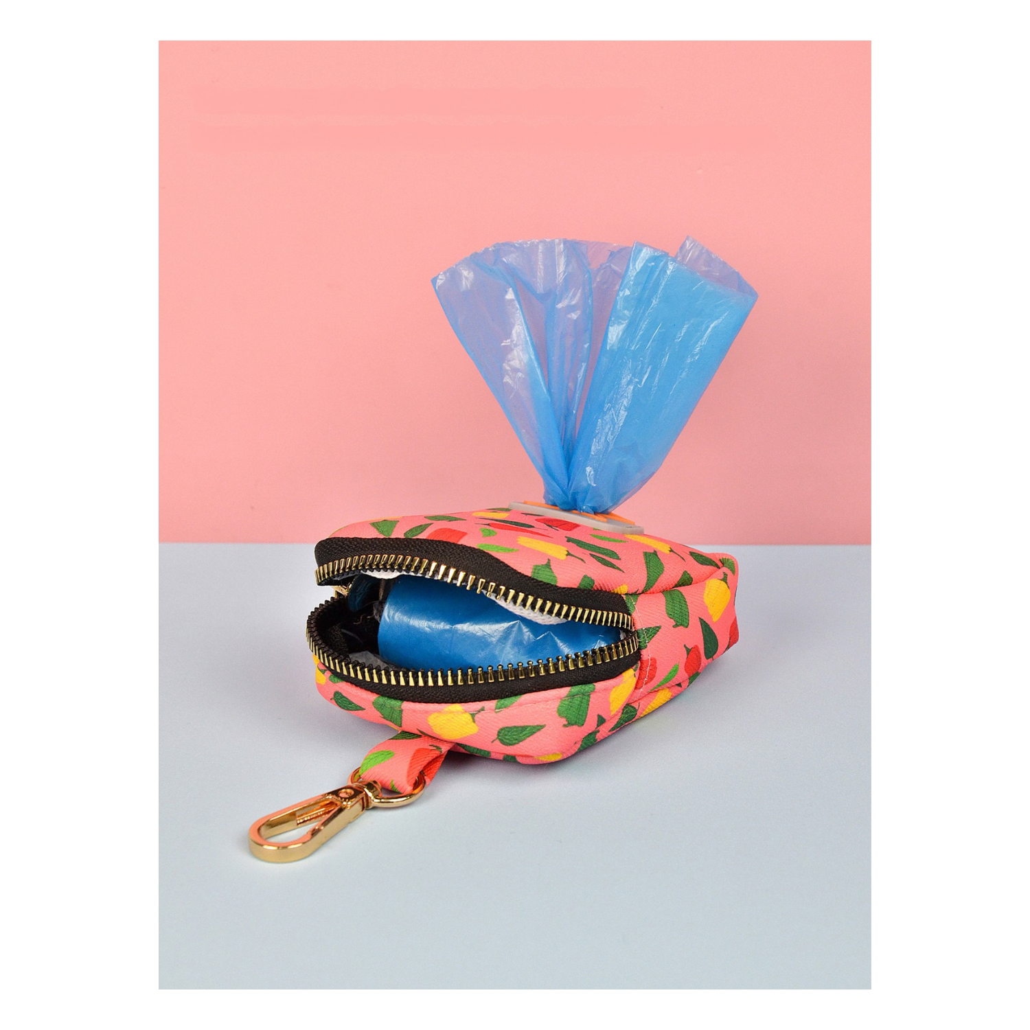 Pochette colorée ouverte contenant des sacs à déjections pour chien avec attache dorée.