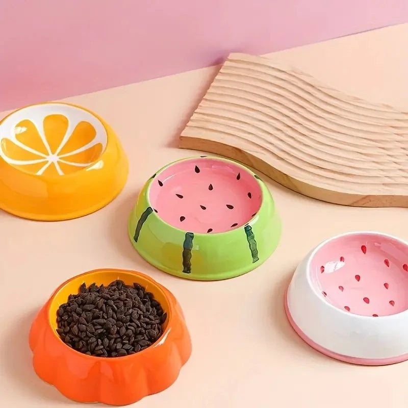 Gamelle en céramique pour chien motif pastèque, orange et fraise avec grains de croquettes.