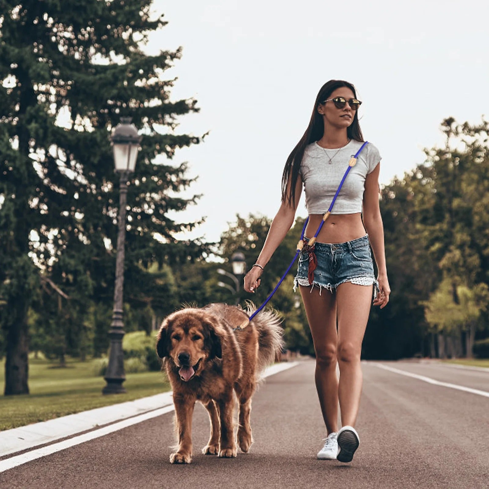 Laisse double bleue avec collier pour chien tenue par femme en tenue décontractée.